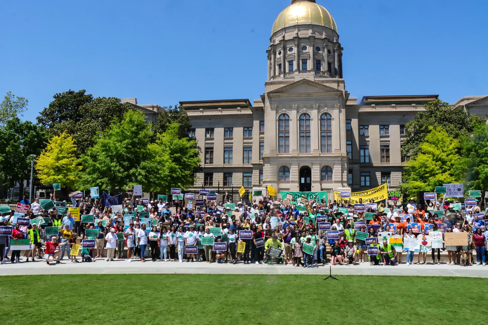 Large group of 100 plus individuals standing on steps of Georgia courthouse holding up climate change signs