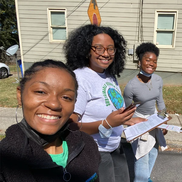 selfie of 3 young ladies walking on street with clipboard volunteering with sustainable georgia futures